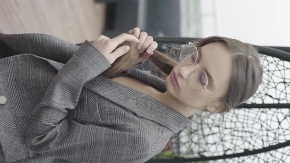 Vertical Video. Beautiful Girl in Glasses and a Gray Suit. Slow Motion