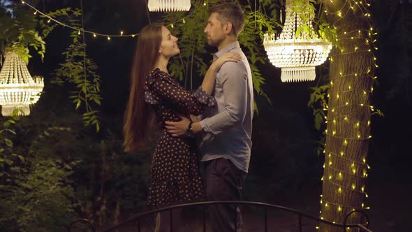 Laughing Loving Couple Hugging in Romantic Pavilion at Night. Portrait of Happy Caucasian Mid-adult