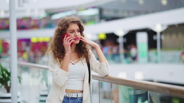 Sad Woman Talking on Phone in Shopping Center
