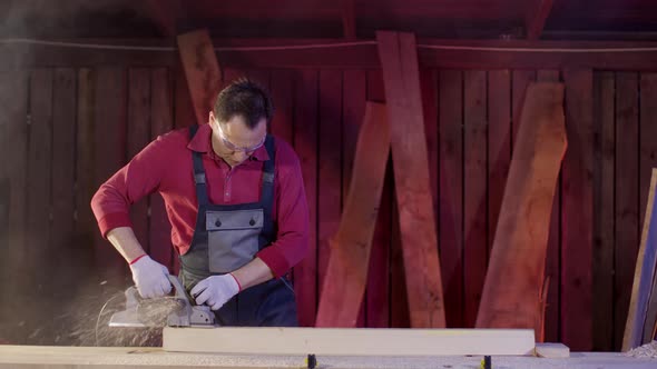 Carpenter Polish the Surface of Wooden Blank with Planer and Flies Sawdust