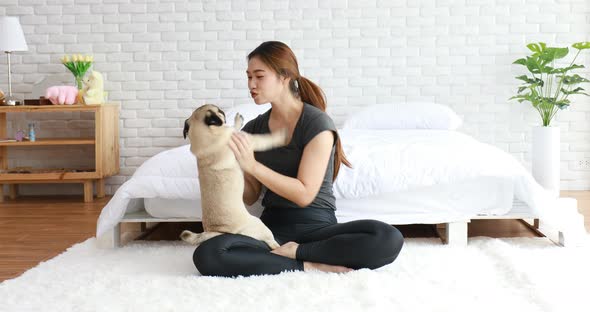 Beautiful Asian young woman playing with her dog and smile with dog pug breed