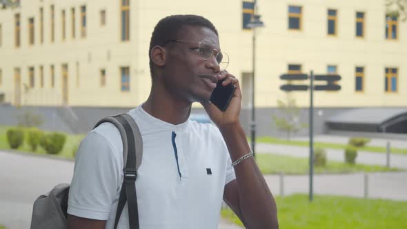 Close-up of Positive African American College Student Talking on the Phone As Little Girl Strolling