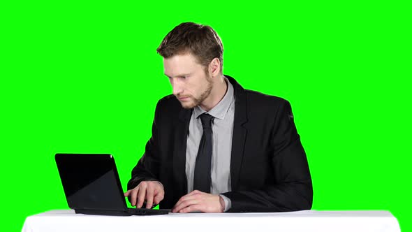 Businessman Sitting at the Table and Uses Notebook. Green Screen