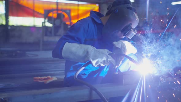 asian male technician worker in a dressed in protective uniform welding metal frame