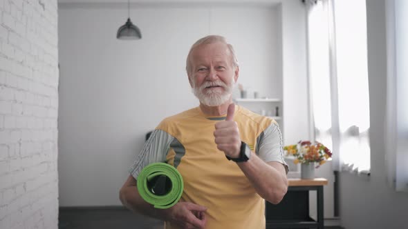 Health Care, Handsome Smiling Old Man in Great Shape with a Yoga Mat in Hands and Smart Watch After