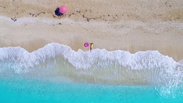 Aerial View of Young Woman with Pink Swim Ring on the Sandy Beach