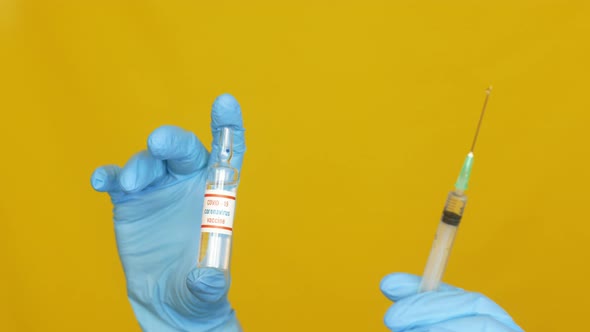 doctor's hands in gloves hold a coronavirus vaccine and a syringe with an injection