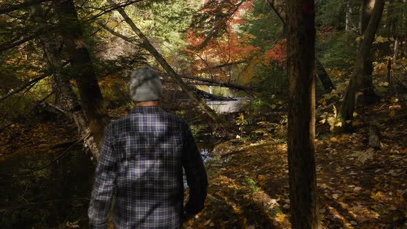 Man in Blue Plaid Hikes in Fall Forest Colors, Slow Motion Handheld. Caucasian Male walks by Calm Ri