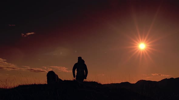 A Man Runs With His Dog At Sunset In The Mountains