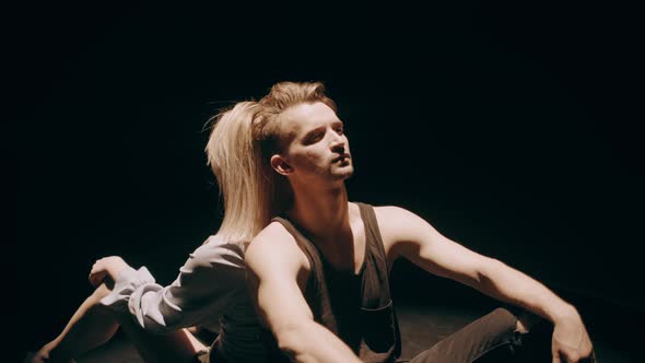 Sad Young Couple Sitting on Dark Background. Couple in a Modern Common Phase of Mutual Disinterest