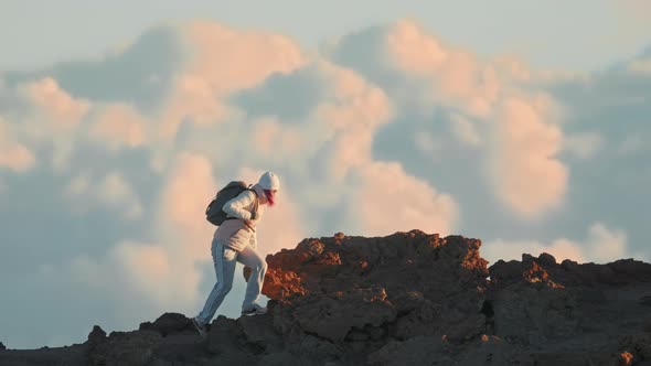 Slow Motion Hiker with Backpack Climbing Volcano Peak Cloudscape on Background