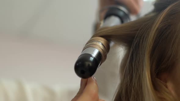 Closeup View of Stylist Hairdresser Making Hairstyle Using Curling Tongs