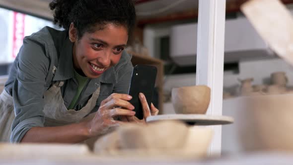 Woman potter filming a spinning clay cup