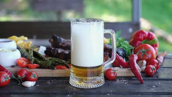 Pouring Beer Into Glass Mug with Delicious Beef or Pork Frying Ribs on Background