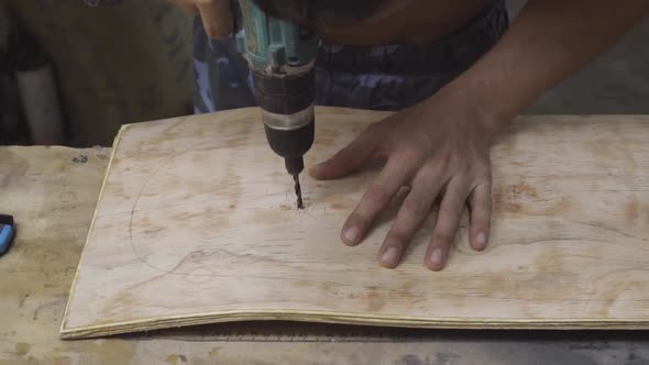Caucasian male hands drilling into a curved wooden board. Slow motion
