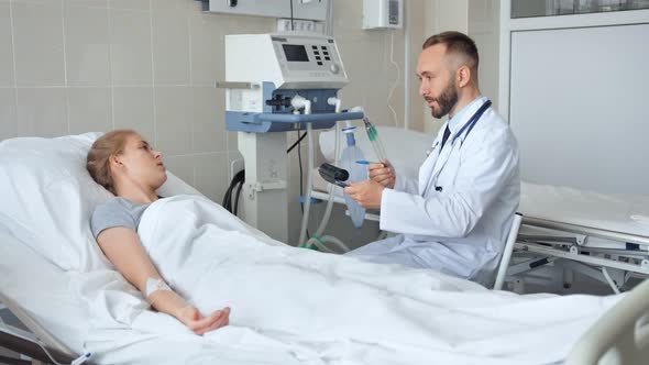 Doctor Sitting Near Hospital Bed and Discussing with Young Female Patient