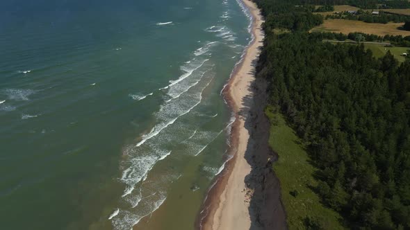 Pan Up: Amazing Drone Fligh Above Turquoise Baltic Sea with Waves and Sand Cliff