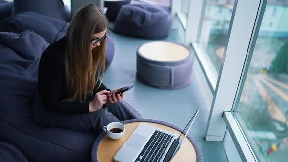 Beautiful young woman working on laptop computer while drinking coffee