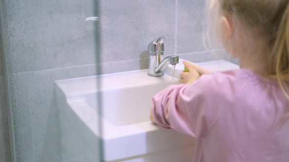 Child Blonde Girl Washing Hands with Green Soap in Modern Bathroom