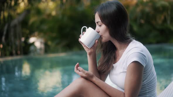 Pretty Brunette Lady Drinks Tea From Mug By Swimming Pool