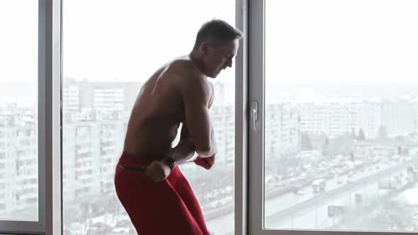 Muscular Man Jumps Over Rope with an Endurance on Background of Panoramic Windows