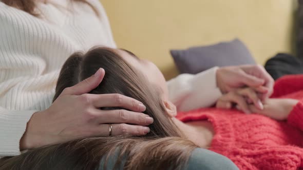 Girl Lies with Her Head on Her Mother's Feet While They Have a Friendly Conversation