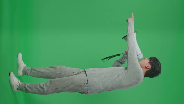 Full Body Of Side View Of An Asian Man Shouting On Megaphone In The Green Screen Studio