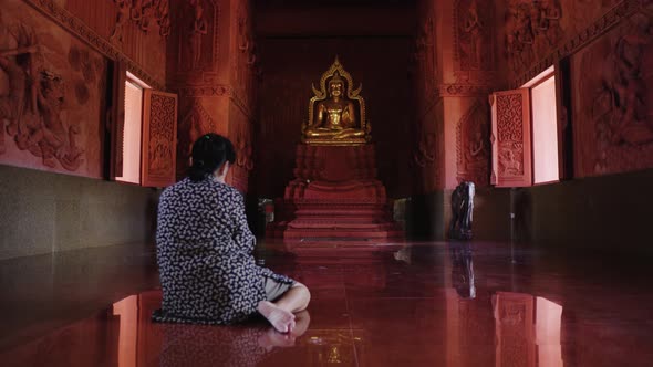 Asian woman prays in Thai Buddhist temple