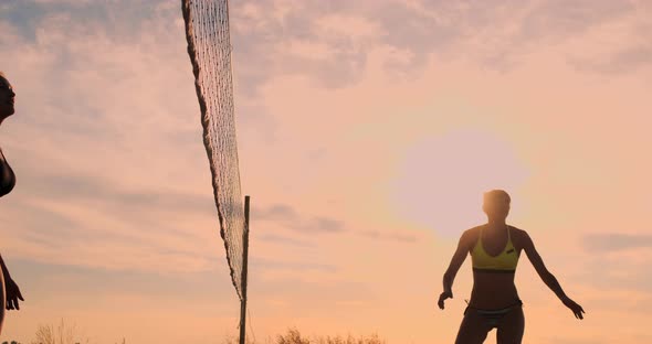 Group of Young Girls Playing Beach Volleyball During Sunset or Sunrise.