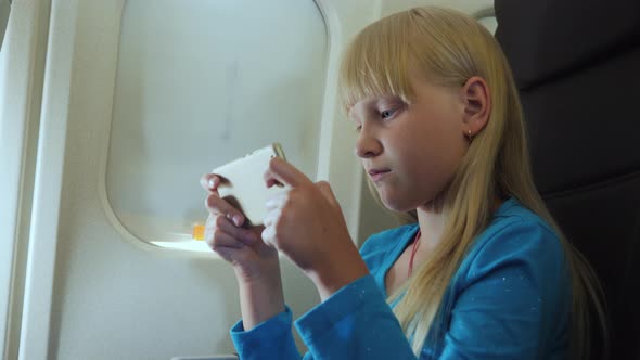 The Child Plays on the Smartphone in the Cockpit