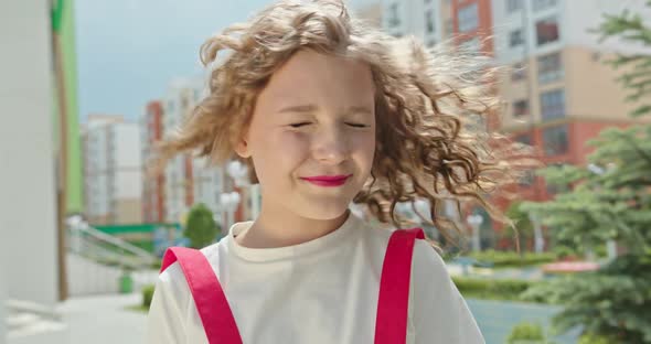 Beautiful Little Girl with Blond Curly Hair Smiles Shakes Her Head in Bright Pink Clothes and Poses