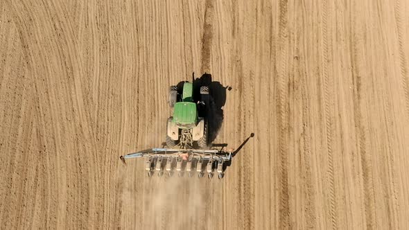 Aerial view large tractor cultivating a dry field. Top down aerial view tractor cultivating ground 