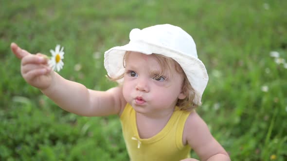 Little Funny Cute Blonde Girl Child Toddler in Yellow Bodysuit and White Hat Walking in Field with