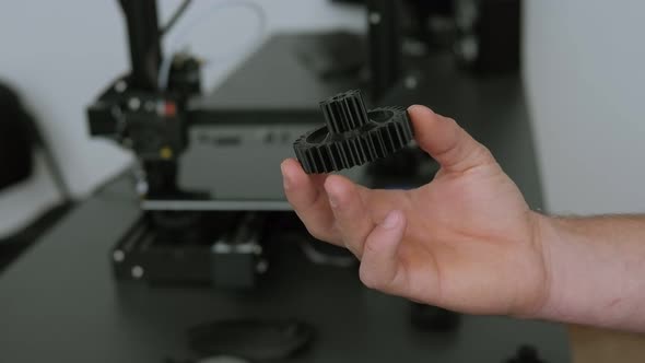 Close-up of a Male Engineer Demonstrates Plastic Models Printed on a 3D Printer