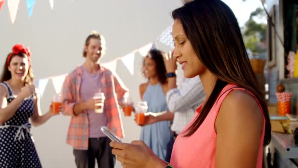 Beautiful woman using mobile phone near food truck