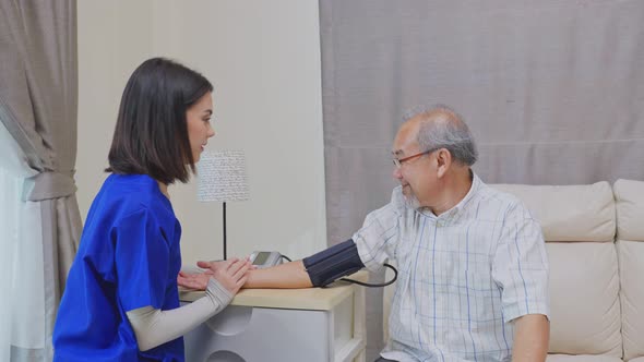 Asian young Caregiver Therapist doctor examining an older patient use blood pressure gauge.