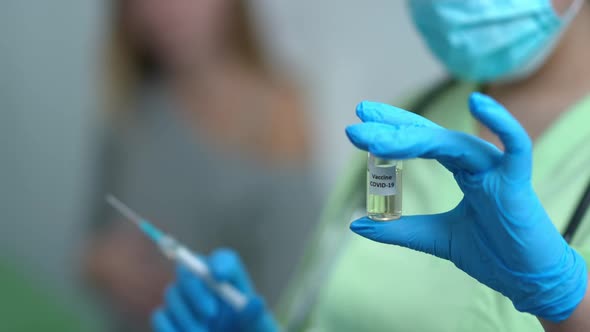 Closeup Coronavirus Vaccine in Hands of Doctor Preparing Jab for Pregnant Blurred Woman Waiting at