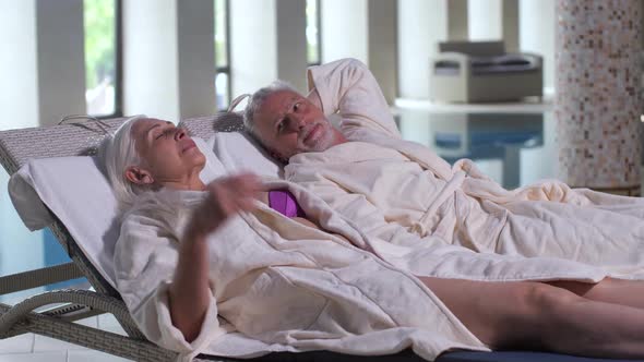 Aging Couple Relaxing on Sunbeds By Pool in Hotel