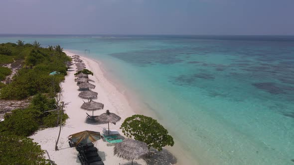 View of blue lagoon beach with umbrellas and sun loungers on maldives island
