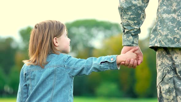 Daughter Holding Hand of Her Military Father.