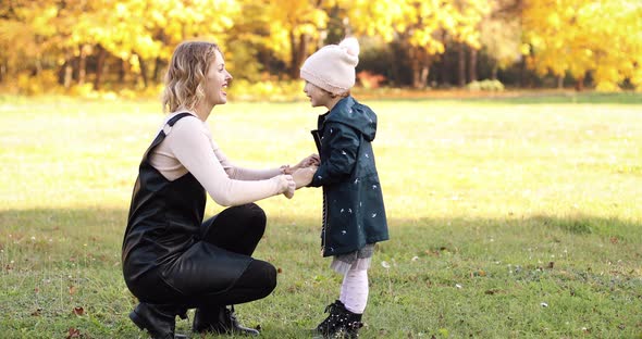 Loving Happy Mother with Her Daughter in Autumnal Park