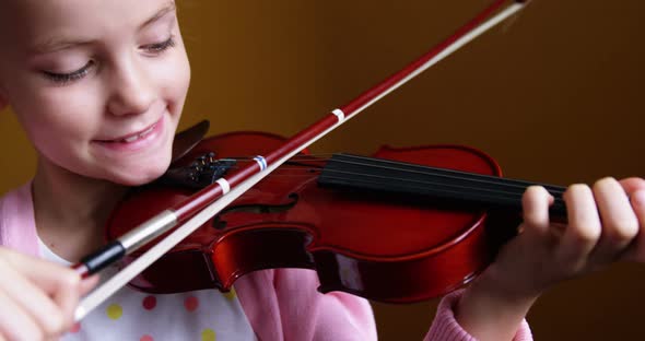 Schoolgirl playing violin in classroom at school