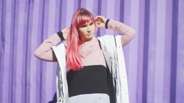 Portrait of Independent Young Woman with Pink Hair Posing on Purple Containers Background