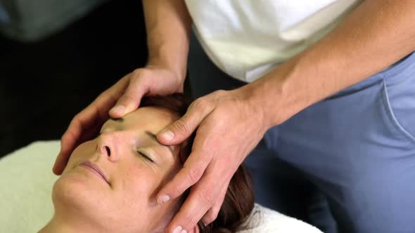 Physiotherapist giving head massage to a female patient