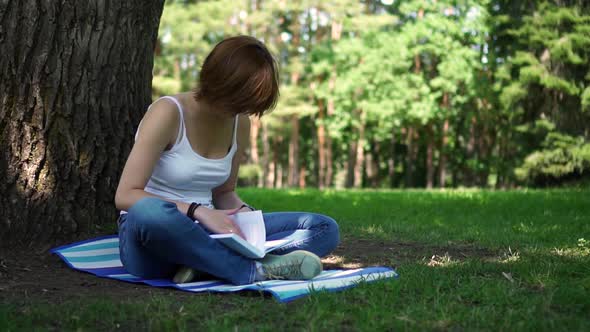 Girl Sitting in the Park Reading a Book