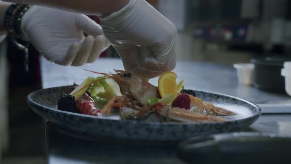 A professional Italian chef is preparing a tasty fish plate with scampi, salad and fruits - 02