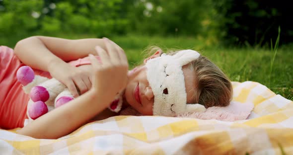 Teenage Girl Rests in Nature Putting on Sleep Mask and Enjoying on a Duvet