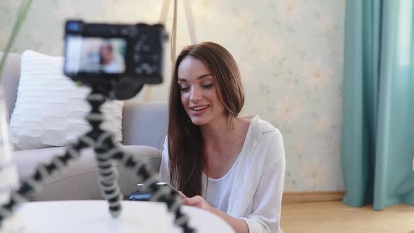 Video blogging. Woman blogger filming on camera at home