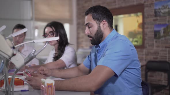 Side View of Exhausted Middle Eastern Man Looking at Teeth Cast and Sighing. Tired Male Dentistry