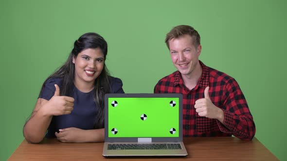 Young Multi-ethnic Business Couple Together Against Green Background